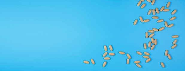 Herbal pills with healthy medical plant. Healthy supplement on blue background.