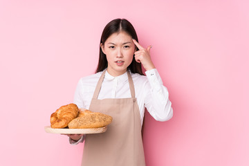 Young chinese baker woman isolated showing a disappointment gesture with forefinger.