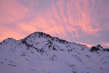 colorful dusk with light clouds and snowy mountains in the foreground