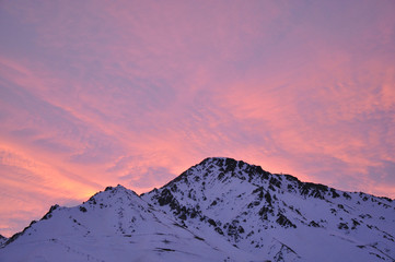 colorful dusk with light clouds and snowy mountains in the foreground