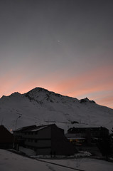 winter sunset over snowy mountain and the moon in the background
