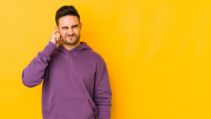 Young caucasian man isolated on yellow bakground covering ears with fingers, stressed and desperate...