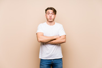 Young caucasian man posing isolated blows cheeks, has tired expression. Facial expression concept.