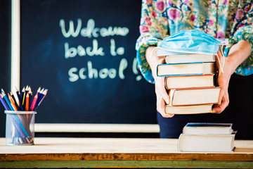 back to school concept during covid - pile of books and medical mask