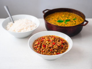 Vegetarian Vegan Indian Buffet of Chick Pea and Spinach Curry, White Rice and Lentil Dhal Stew in Various Pots and Bowls on a White Background
