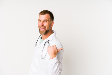 Senior doctor man isolated on white background points with thumb finger away, laughing and carefree.