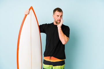 Surfen man isolated on blue background is saying a secret hot braking news and looking aside