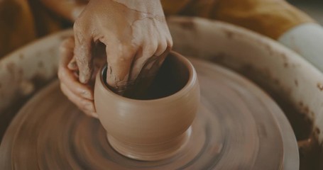 Talented woman making clay bowl on pottery wheel, close up of hands and clay, handmade