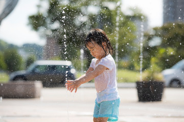 広場の噴水で水遊びする子供