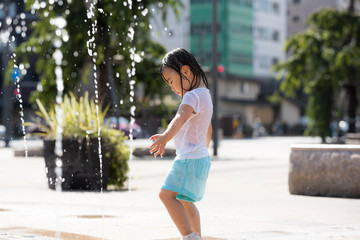 広場の噴水で水遊びする子供