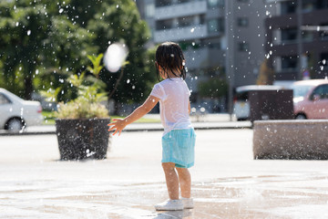 広場の噴水で水遊びする子供
