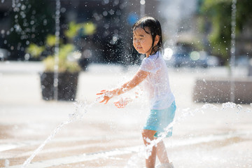 広場の噴水で水遊びする子供
