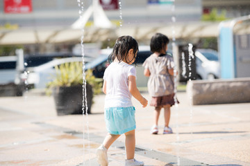 広場の噴水で水遊びする子供