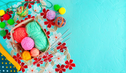 Knitting yarn on a textured background. Multi-colored yarn for knitting in a basket on a turquoise background. Needlework in the form of knitting.