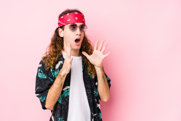 Young hippie caucasian man isolated shouts loud, keeps eyes opened and hands tense.