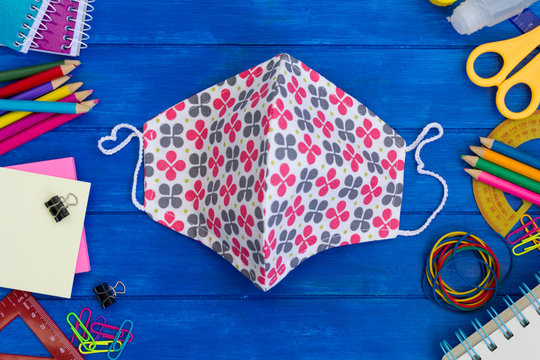 School supplies and cloth masks on blue wooden table. Back to school during covid-19 pandemic, new normal concept