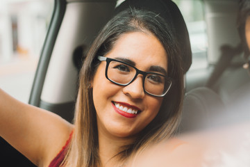 Mujer joven mexicana latina sonríe en pease en auto en dia soleado 