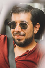Obraz premium Joven adulto mexicano latino en auto usando cinturón de seguridad en dia de vacaciones