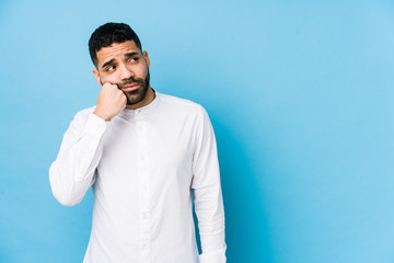 Young latin man against a blue  background isolated who feels sad and pensive, looking at copy space.