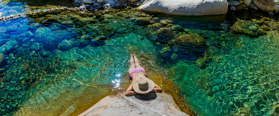 Woman with hat bathing in a turquoise green river