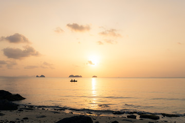 Couple kayaking on the sea against the backdrop of islands and golden sunset