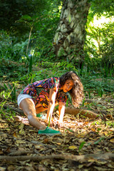 chica con camisa de cuadros de colores sonriendo sobre un árbol en una escena de naturaleza en sevilla, españa. 