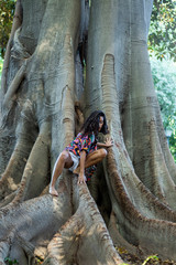 chica con camisa de cuadros de colores sonriendo sobre un árbol en una escena de naturaleza en sevilla, españa. 