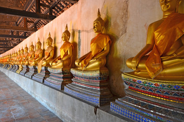 Row of golden Buddha images on beautiful base in Thai temple