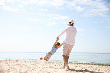 Grandfather playing with little boy on sea beach