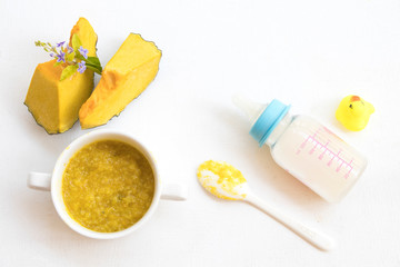 mix rice gruel with  pumpkin healthy foods health care for baby eats breakfast and milks bottle arrangement flat lay style on background white 