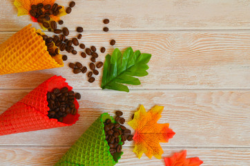 Autumn background with space for text waffle cones with coffee beans and autumn maple leaves flat lay top view