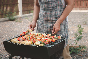 A man grilling pork and barbecue in dinner party. Food, people and family time concept.