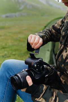 Crop anonymous male photographer in jeans and khaki jacket inserting memory card into photo camera while working in nature