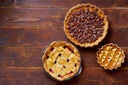 Variety of thanksgiving pies on wooden table.