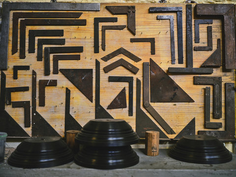 Set of metal corners of various sizes arranged on wooden board near professional tools in goldsmith workshop