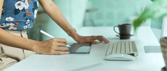 Female fashion designer working with digital tablet with stylus pen on computer desk