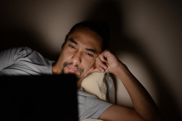 young latin man watching his tablet in bed.