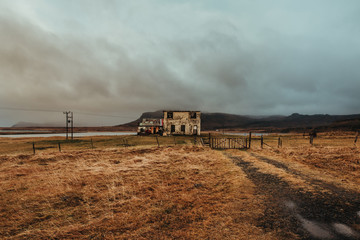Old partially destroyed construction in field near mountains covered with fog under sky with low clouds in autumn in Iceland