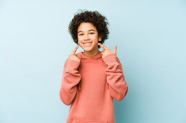 African american little boy isolated smiles, pointing fingers at mouth.