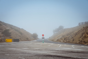 Round red prohibitory road sign with word stop on empty asphalt roadway in dry rural terrain