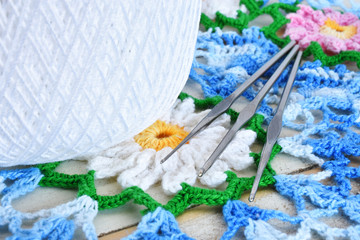 A close up image of three metal crochet hooks on a blue and white crochet doily. 