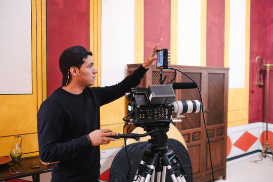 Side view of male video operator broadcasting live event and looking at display on camera