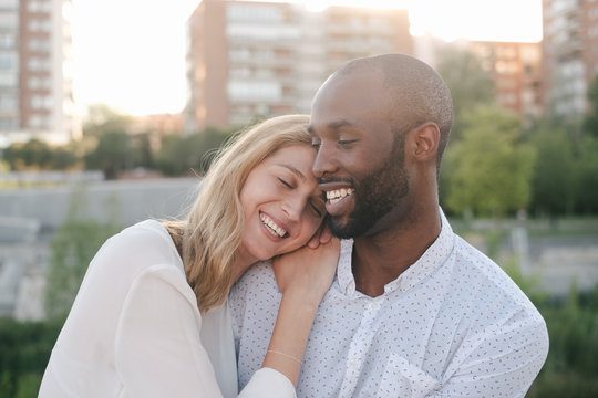 Content black boyfriend and smiling girlfriend while bonding sensually and cuddling together in daytime