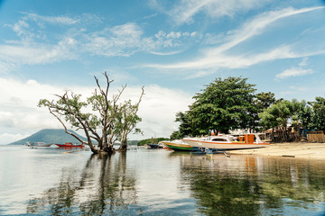 Picturesque seascape of mountain top and boats floating on clear water of sea against blue sky