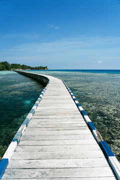 Long wooden embankment going through clear water of sea on sunny day in summer