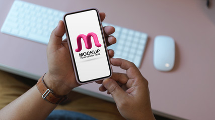 Overhead shot of male office worker holding mock up smartphone