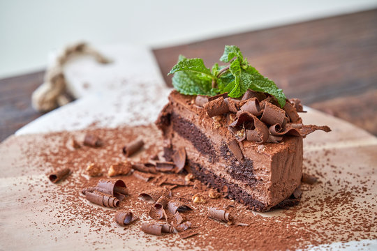 Delectable halved chocolate mousse cake with garnished with fresh mint leaves served on wooden board on table