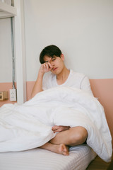 A dozy guy sitting on the bed.