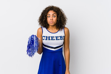 Young african american cheerleader woman isolated shrugs shoulders and open eyes confused.