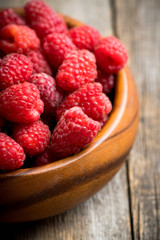Red ripe raspberry in wooden bowl on the rustic background. Selective focus. Shallow depth of field. 